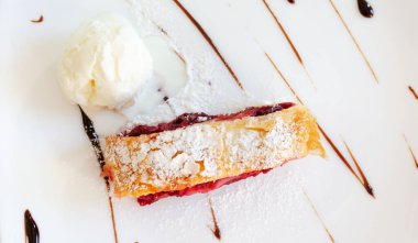 Beyaz tabakta bir kepçe dondurmayla vişneli turta. Geleneksel hamur işleri kavramı. Yatay oryantasyon. Üst görünüm.