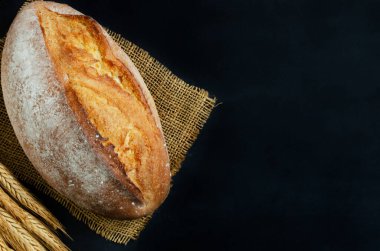 Çuval bezinde taze ekmek ve siyah arka planda bir çuval bezi. Kırsal tarzda. Ev yapımı kavramı. Yatay oryantasyon. kopyalama alanı. Üst görünüm