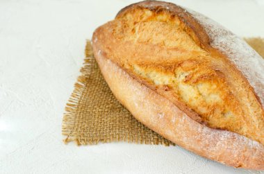 Hafif bir arka planda çuval bezinde taze pişmiş ekmek. Kırsal tarzda. Ev yapımı kavramı. Yatay oryantasyon. Boşluğu kopyala