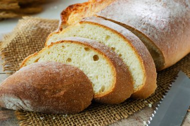 Çuval bezinde taze ekmek dilimleri ve arka planda bir bıçak. Kırsal tarzda. Ev yapımı ekmek kavramı. Yatay yönelim.