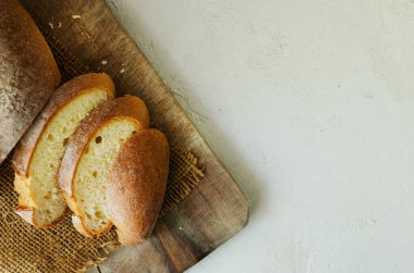 Hafif bir arka planda tahta bir kesme tahtasının üzerinde taze pişmiş ekmek dilimleri. Kırsal tarzda. Ev yapımı ekmek kavramı. Yatay oryantasyon. Üst Manzara. Boşluğu kopyala.