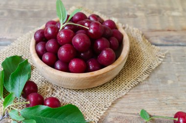 Tahta bir masadaki ahşap bir kasede bir sürü olgun kırmızı kiraz. Organik tarım kavramı. Yatay yönelim.