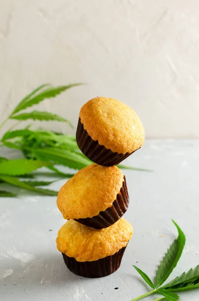 Three Marijuana cupcake muffins with cannabis leaves. Gluten free. Alternative sweets concept. Vertical orientation. Selective focus.