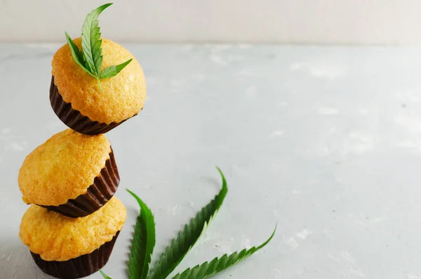 Three Marijuana cupcake muffins with cannabis leaves. Gluten free. Alternative sweets concept. Horizontal orientation. Selective focus. Copy space