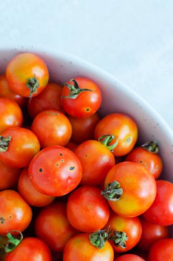 Small ugly red and yellow tomatoes in a pink plate. Farm to table concept. Farming. Vertical orientation. Top view. Selective focus