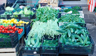 Sokak pazarında çeşitli sebzeler. Momordika yeşili, kuşkonmaz, domates ve limon. Sağlıklı beslenme kavramı. Yatay yönelim.
