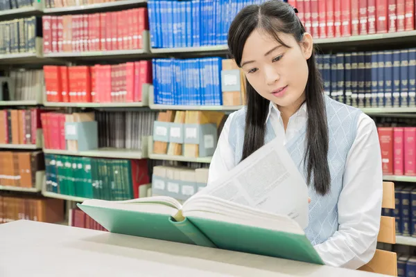 Estudiante asiático leyendo libro en biblioteca en la universidad — Foto de Stock