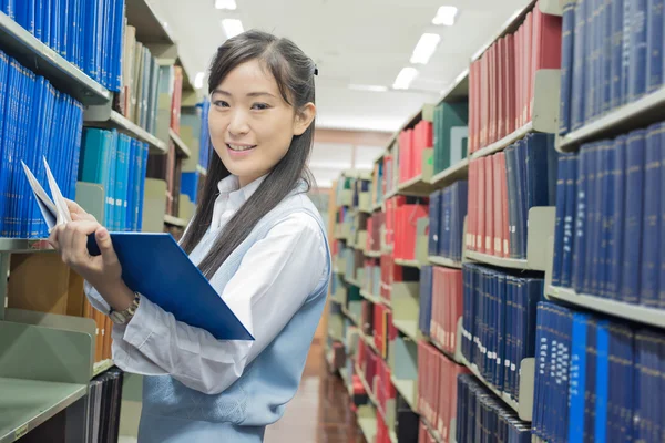 Estudante asiático leitura livro na biblioteca na universidade — Fotografia de Stock