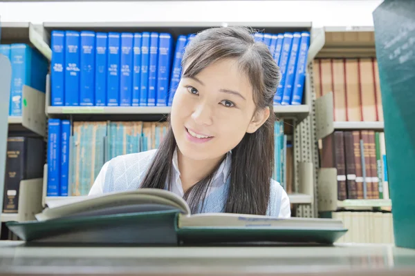 Asiatico studente lettura libro in biblioteca a università — Foto Stock