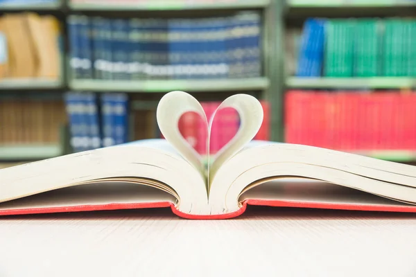 Páginas de livros em forma de coração com fundo de biblioteca — Fotografia de Stock