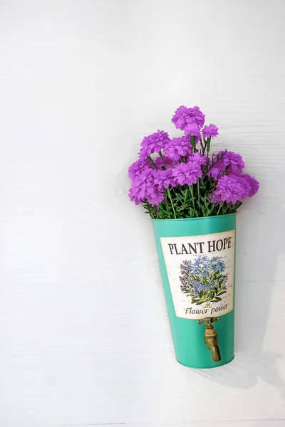 Цветочный горшок с фиолетовыми цветами висит на стене дома — стоковое фото