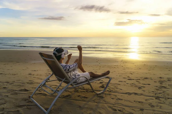 美しい海と空を背景に熱帯のビーチでビジネスミーティングのための仮想現実の眼鏡を使用して若いアジアの男 — ストック写真