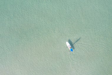 Asyalı bir adamın yaz günü turkuaz tropikal berrak sularda yiyecek tatbikatı yaptığı hava manzarası.