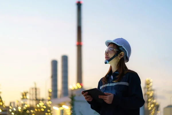 デジタルタブレットで夜間作業するアジアの女性石油化学エンジニア検査官の安全品質管理のために夜の石油 ガス精製プラント産業工場内 — ストック写真