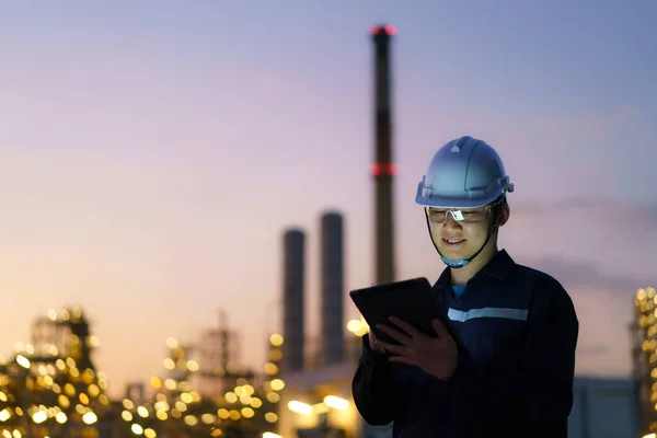 デジタルタブレットを介して夜の石油精製工場のメンテナンスをチェックするアジアのエンジニアの男 — ストック写真