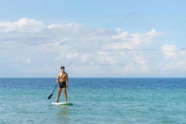 Asyalı bir adam yaz günü turkuaz tropik berrak sularda yiyecek tatbikatı yapıyor.