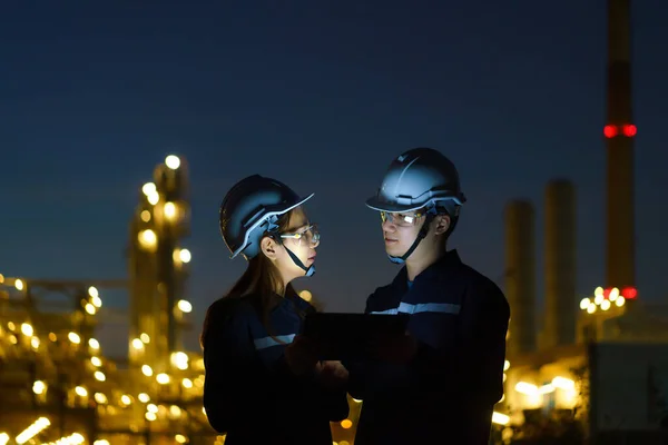 アジアのエンジニア 男性と女性は デジタルタブレットを介して夜の石油精製工場のメンテナンスをチェックしています — ストック写真