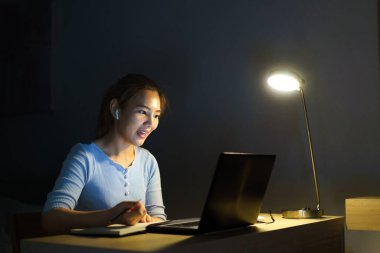 Evde çalışan Asyalı kadın, iş yerinde iş arkadaşları veya yöneticilerle birlikte gece evde video görüşmesi yapıyor.