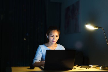 Evde çalışan Asyalı kadın, iş yerinde iş arkadaşları veya yöneticilerle birlikte gece evde video görüşmesi yapıyor.