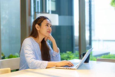 Evde dizüstü bilgisayarla çalışan zeki bir Asyalı kızın portresi. Oturma odasında. Coronavirus veya Covid-19 salgını hakkında bir şeyler düşün.