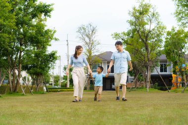 Asyalı bir aile, hem fiziksel hem de zihinsel açıdan mutlu bir aile olarak günlük sağlık ve refah için bahçelerde ya da halka açık bir parkta yürüyor..