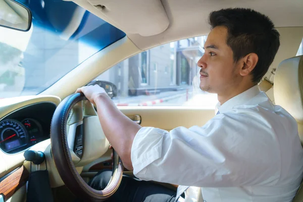 年轻的亚洲人一边微笑着 一边看着城市道路 一边开车 — 图库照片