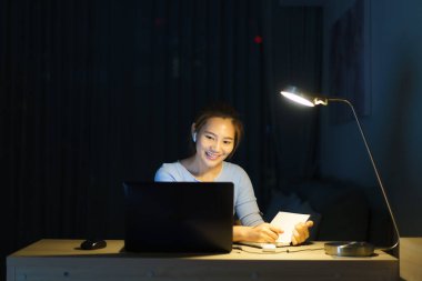 Evde çalışan Asyalı kadın, iş yerinde iş arkadaşları veya yöneticilerle birlikte gece evde video görüşmesi yapıyor.