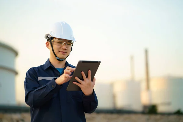 アジアのエンジニアの男性は デジタルタブレットを介して夕方に石油精製工場のメンテナンスをチェックしています — ストック写真