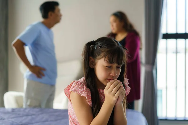 Family violence and family conflict concept, sad little girl with blur of mother fighting father with quarrel at home.