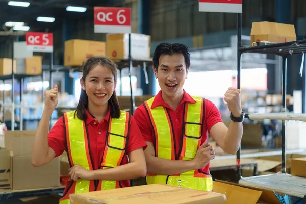 Asian couple warehouse worker smiling and arm raised at counter already preparation container box goods deliverly to customer.