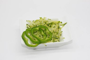 Beyaz arka planda izole edilmiş bir kasede kabak tadı ve dolmalık biber dilimleri.