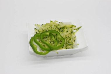 Beyaz arka planda izole edilmiş bir kasede kabak tadı ve dolmalık biber dilimleri.