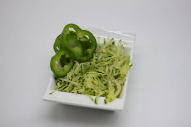 Beyaz arka planda izole edilmiş bir kasede kabak tadı ve dolmalık biber dilimleri.