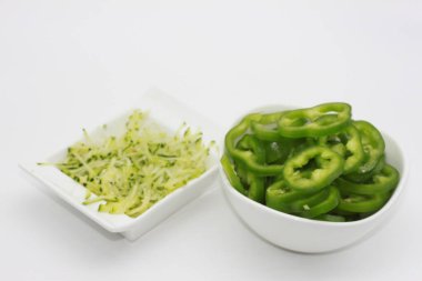 Beyaz arka planda izole edilmiş bir kasede kabak tadı ve dolmalık biber dilimleri.