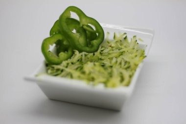 Beyaz arka planda izole edilmiş bir kasede kabak tadı ve dolmalık biber dilimleri.