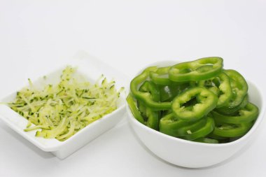 Beyaz arka planda izole edilmiş bir kasede kabak tadı ve dolmalık biber dilimleri.