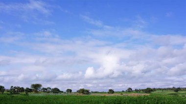 Kenya 'daki kırsal alanların bulanık görüntüsü, mavi gökyüzü ve beyaz bulutlu yeşil alanlar