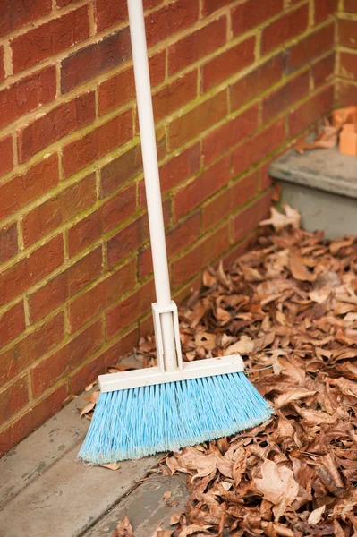 Broom leaning on brick wall Stock Picture