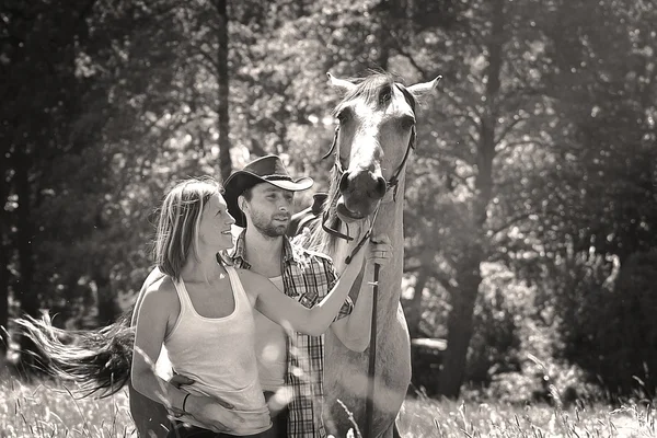 Jeune beau couple baiser avec un cheval au coucher du soleil . — Photo