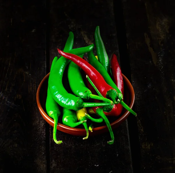 Red And Green Hot Chili Peppers in bowl over wood background — Stok Foto