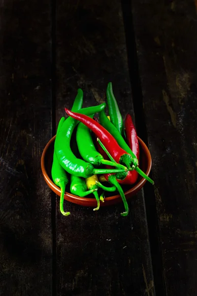 Red And Green Hot Chili Peppers In Bowl Over Wooden Table (selective focus)