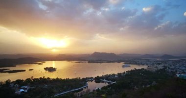 Udaipur şehrinin ufuk çizgisinin gün batımı görüntüsü ve Udaipur 'un bakış açısından görülen Pichola gölünün hızlandırılmış 4K görüntüsü. Udaipur şehri, Rajasthan, Hindistan