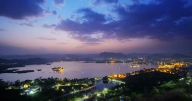 Udaipur şehrinin ufuk çizgisinin gün batımı görüntüsü ve Udaipur 'un bakış açısından görülen Pichola gölünün hızlandırılmış 4K görüntüsü. Udaipur şehri, Rajasthan, Hindistan