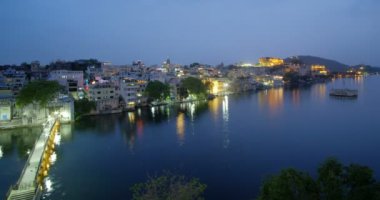 Udaipur şehrinin ufuk çizgisinin akşam manzarası ve Udaipur bakış açısından görülen Pichola gölünün hızlandırılmış 4K görüntüsü. Udaipur şehri, Rajasthan, Hindistan.