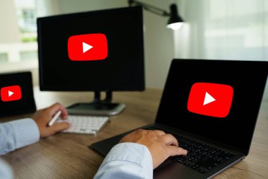 Bangkok, Tayland - 25 Nisan 2022: YouTube sitesinde ekranında YouTube logosu olan bir adam dizüstü bilgisayar kullanıyor. YouTube dünyanın en popüler internet sitesidir.