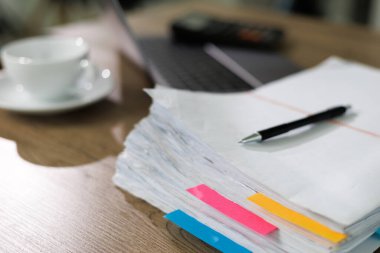 İş kâğıdı yığını. Belgeleri okuyan İşadamı mali durumu işe aktarıyor. Belge planlarını ofis masasında analiz ediyor.