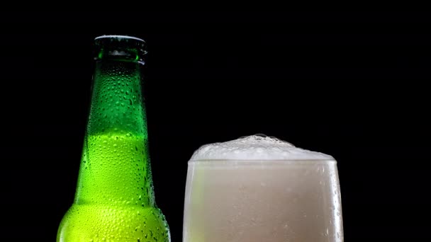 Sörhab öntött egy pohárba. Hideg sör. Zöld sörösüveg. — Stock videók