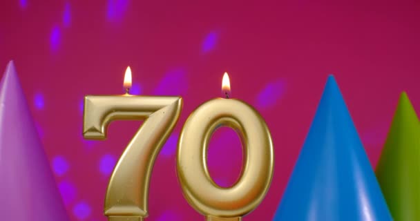70 numaralı doğum günü pastası mumu yanıyor. Mutlu yıllar yıldönümü kutlaması konsepti. Arka planda doğum günü şapkası — Stok video