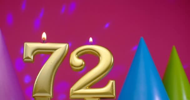 A 72-es számú égő szülinapi torta gyertya. Boldog születésnapot háttér évforduló ünneplés koncepció. Születésnapi kalap a háttérben — Stock videók
