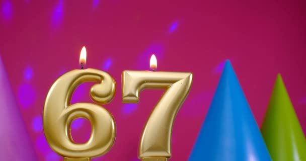 Verbrand verjaardagstaart kaars nummer 67. Gelukkige verjaardag achtergrond jubileum concept. Verjaardagshoed op de achtergrond — Stockvideo